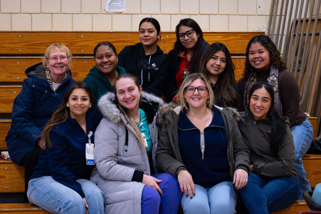 BFX_Staff_Group_shot_optimized_1000 Group of people sitting on bleachers smiling